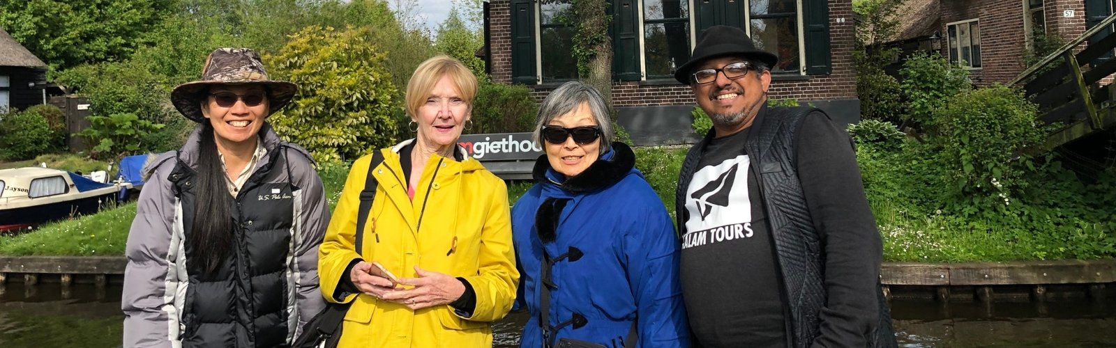 A few tourists casually pose in front of the Giethoorn canal.